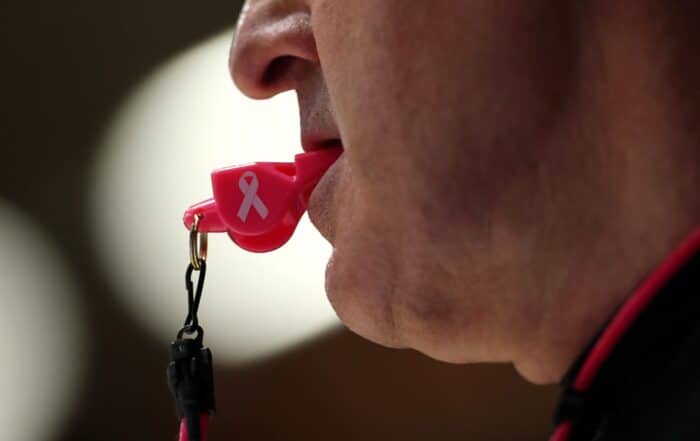 Un arbitre, le sifflet à la bouche.
